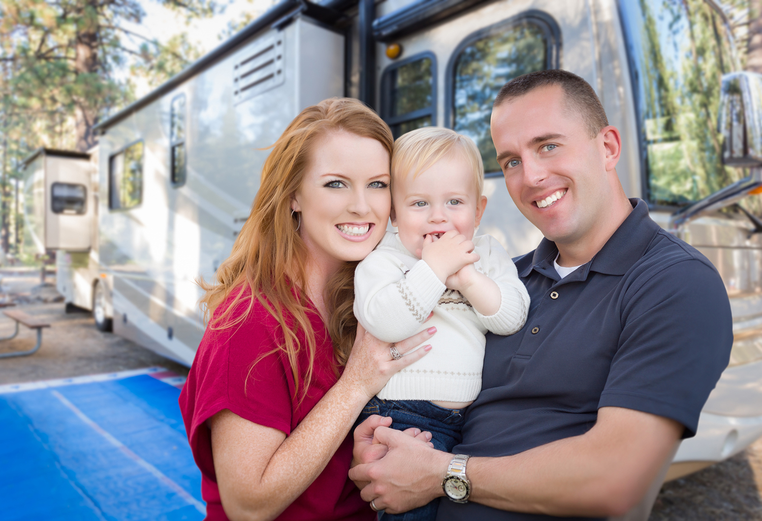Happy couple with their new baby in front of a newly purchased motorhome after an rv inspection services were preformed